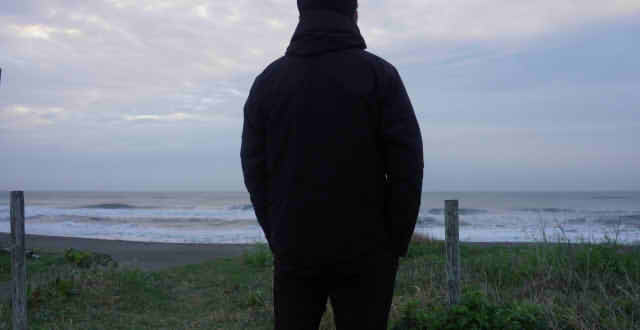海辺を見つめる男性の後ろ姿の画像