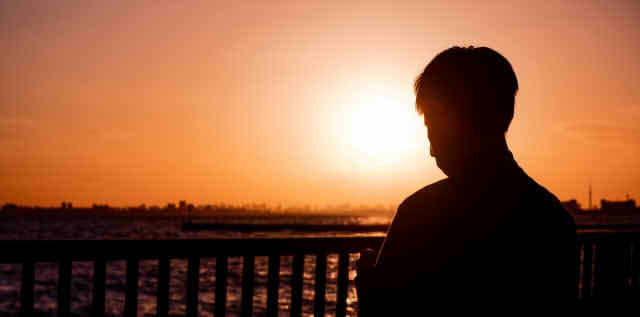 夕日を見つめる男性の画像