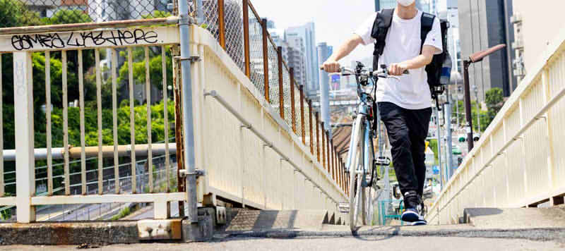 自転車を運ぶ青年の画像