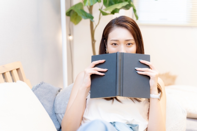 本で口を隠す女性の画像