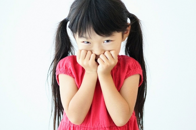 口を両手で抑えている女の子の画像