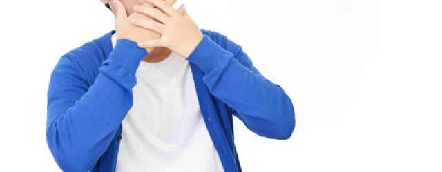 手を口にあてて驚いている男性の画像