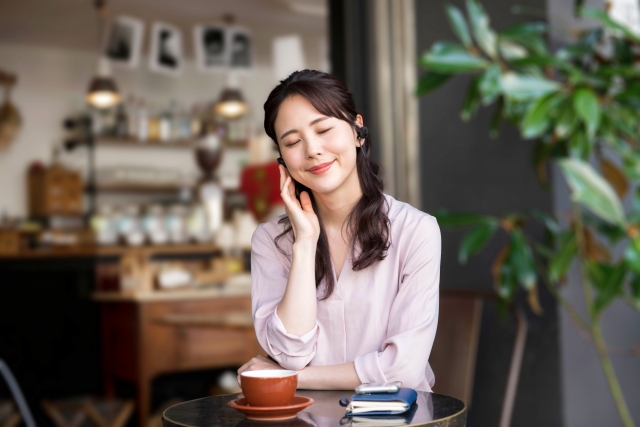 カフェでイヤホンを付ける女性の画像
