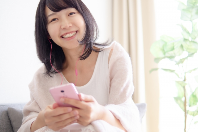 イヤホンをつけてこちらに微笑みかける女性の画像