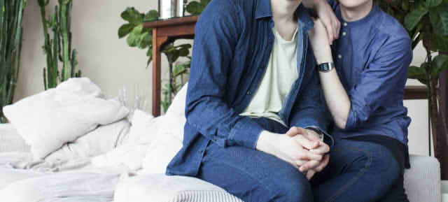 男性二人がソファーで寄り添いあう画像