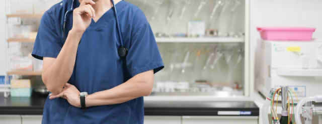 顎に手をあてて悩む男性医師の画像