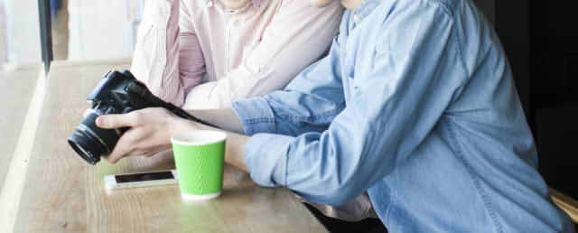 カウンター席で肩を寄せ合いカメラを覗き込む男性二人の画像