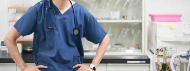 腰に手を置く男性医師の画像