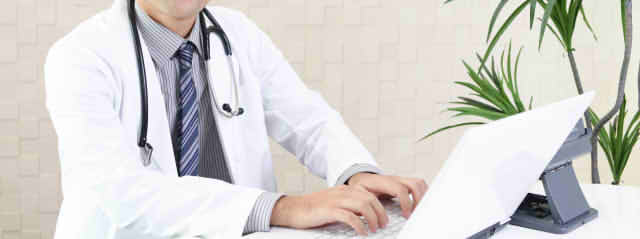パソコンに入力している男性医師の画像