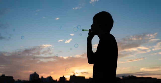 夕暮れにシャボン玉を吹く男性の画像