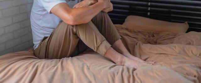 男性がベッドの上で落ち込んでいる様子の画像