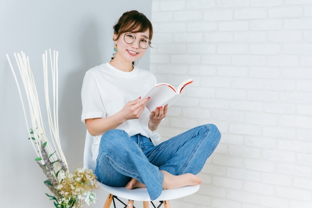 椅子で本を読む女性の画像