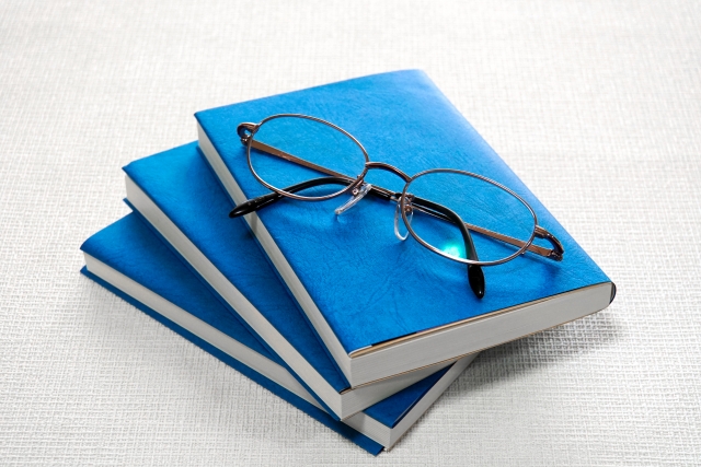 ブックカバーがされている本と眼鏡の画像